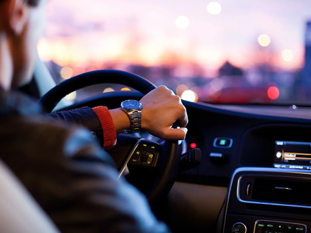 Over the shoulder view of a man driving his car at dusk.