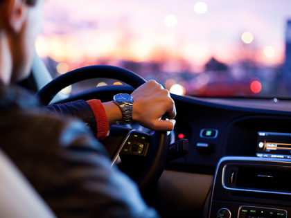 Over the shoulder view of a man driving his car at dusk. 